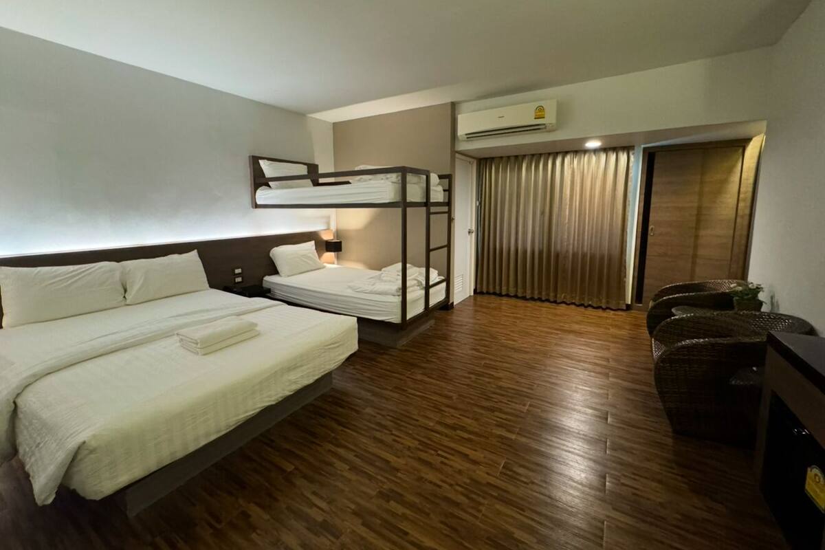 Una habitación de hotel con una cama grande, una cama más pequeña, un sofá y un armario.