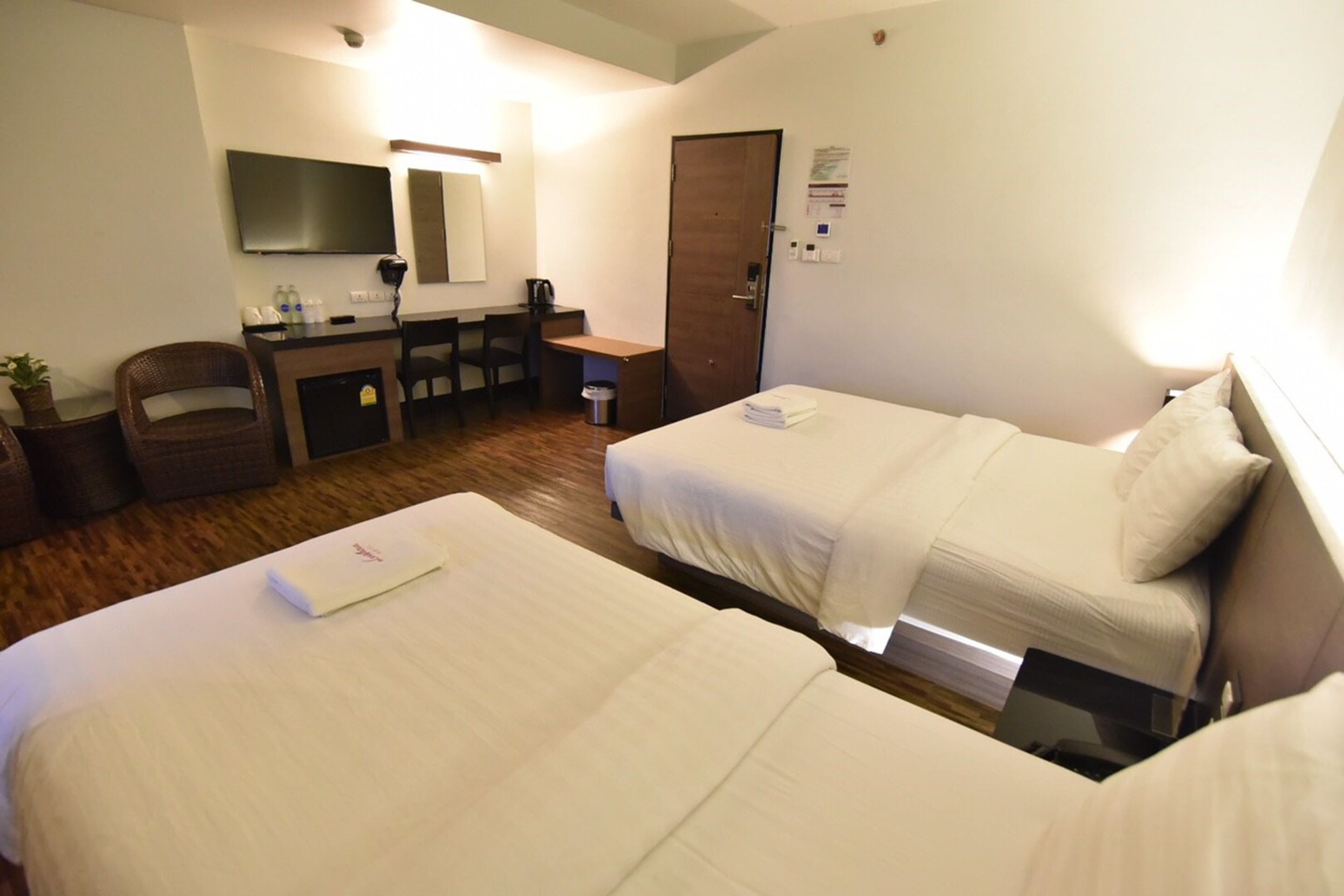 Hotelkamer met twee bedden, een bureau, een stoel, een televisie en een deur.