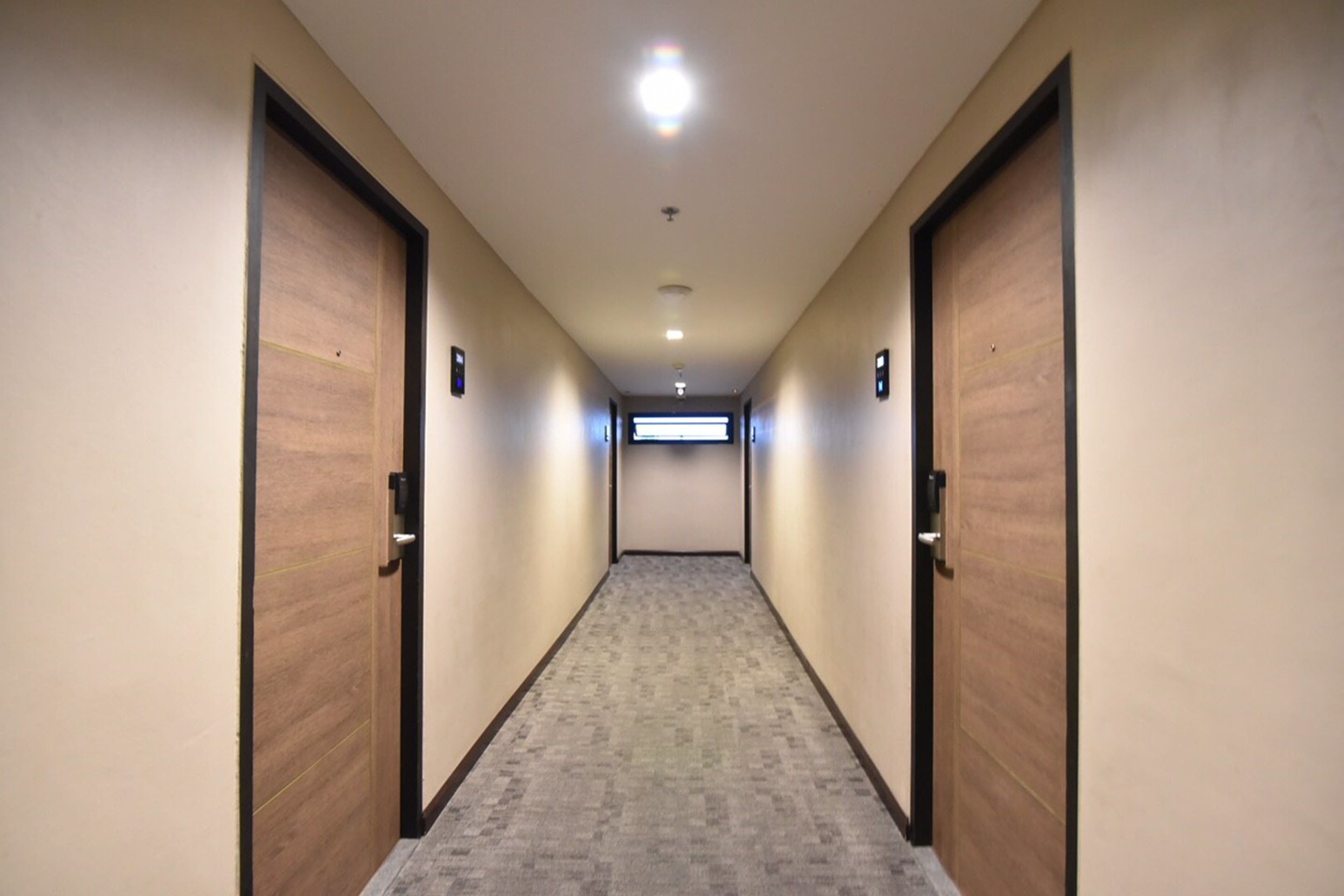 A hallway with wooden doors, carpeted floor, and recessed lighting.