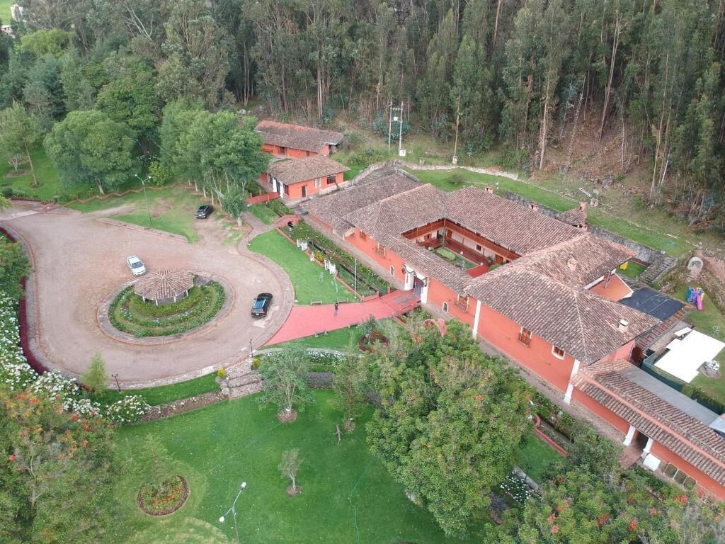 Luchtbeeld van een woonwijk met meerdere huizen, een centrale cirkelvormige oprit en omliggend groen.