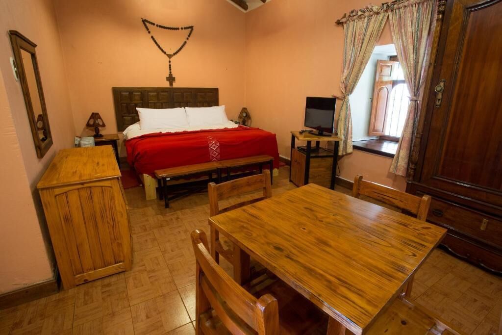 A bedroom with a wooden bed, a wooden table, and a television.