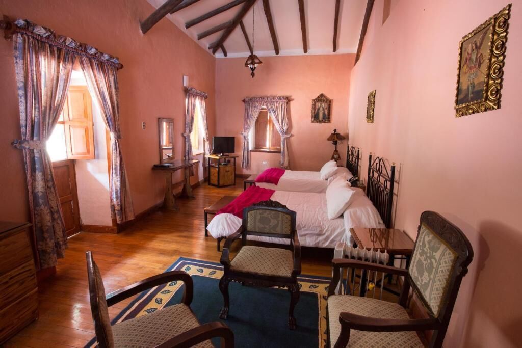 Un dormitorio acogedor con cama, dos sillas, un escritorio y una ventana con cortinas.