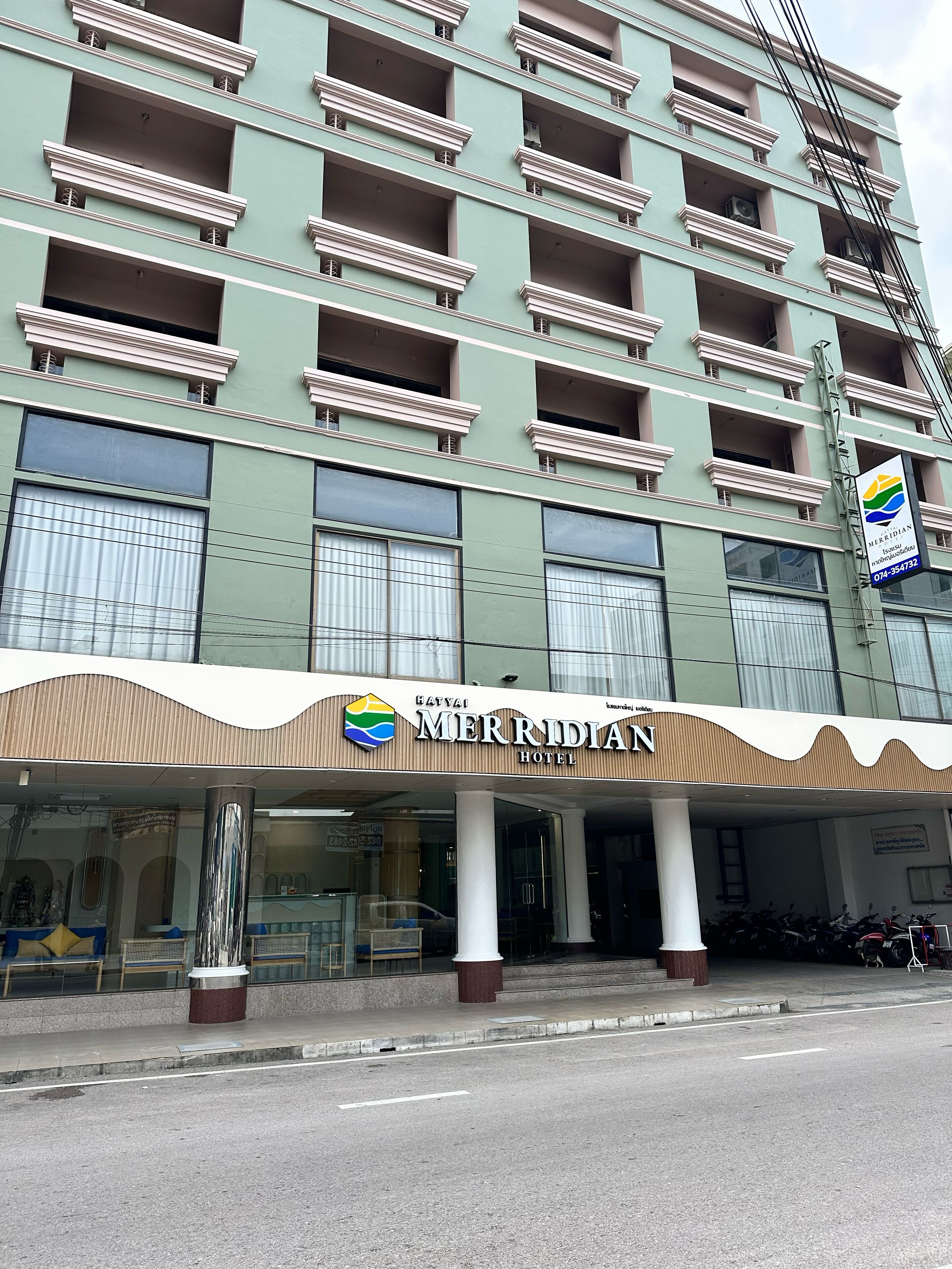 A hotel with a modern facade, multiple balconies, and a prominent sign.