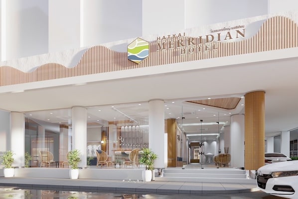 Una entrada de hotel moderna con un letrero destacado que dice "HATYAI MERRIDIAN HOTEL".