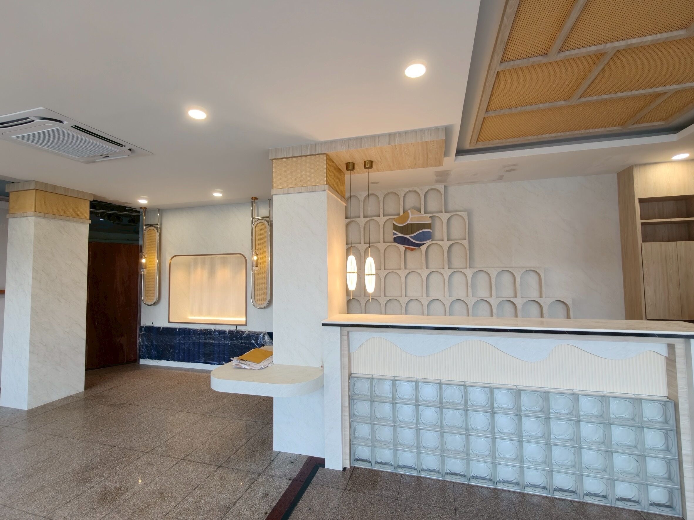 A reception area with a marble floor, a reception desk, a wall-mounted information board, and a ceiling with recessed lighting.