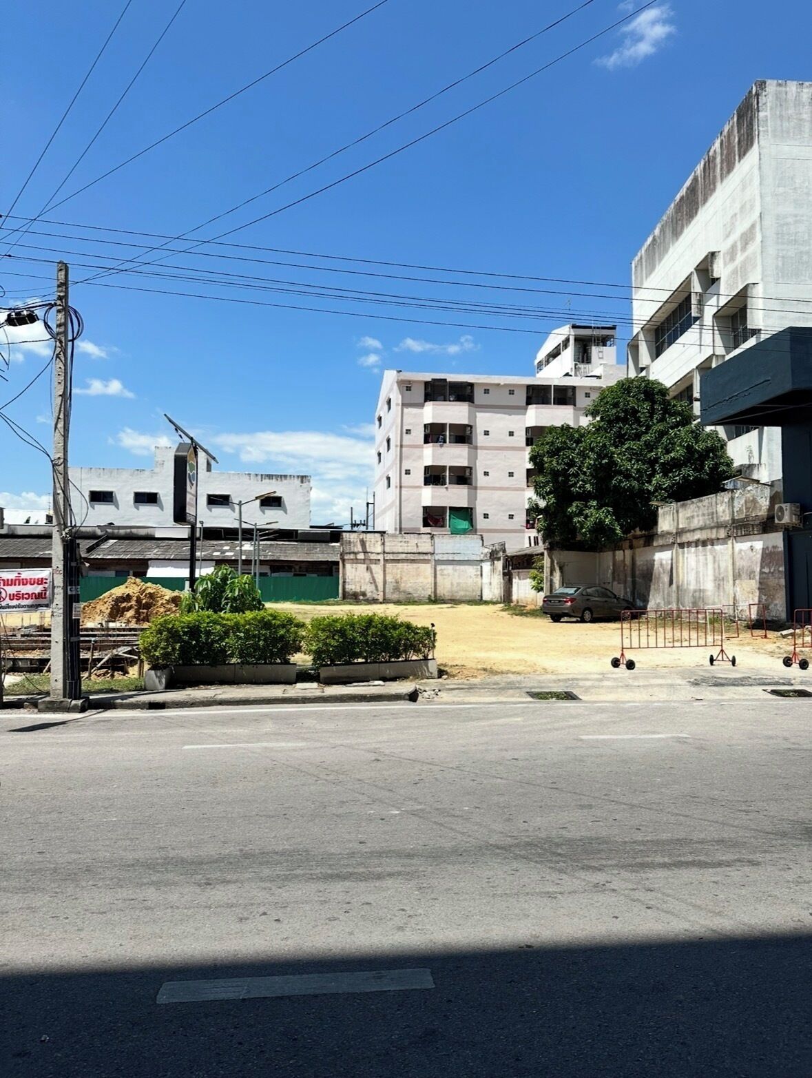 A street view with a multi-story building, a construction site, and a parked car.