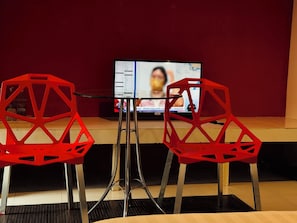 Una habitación con dos sillas rojas, una mesa y un televisor que muestra un mapa.