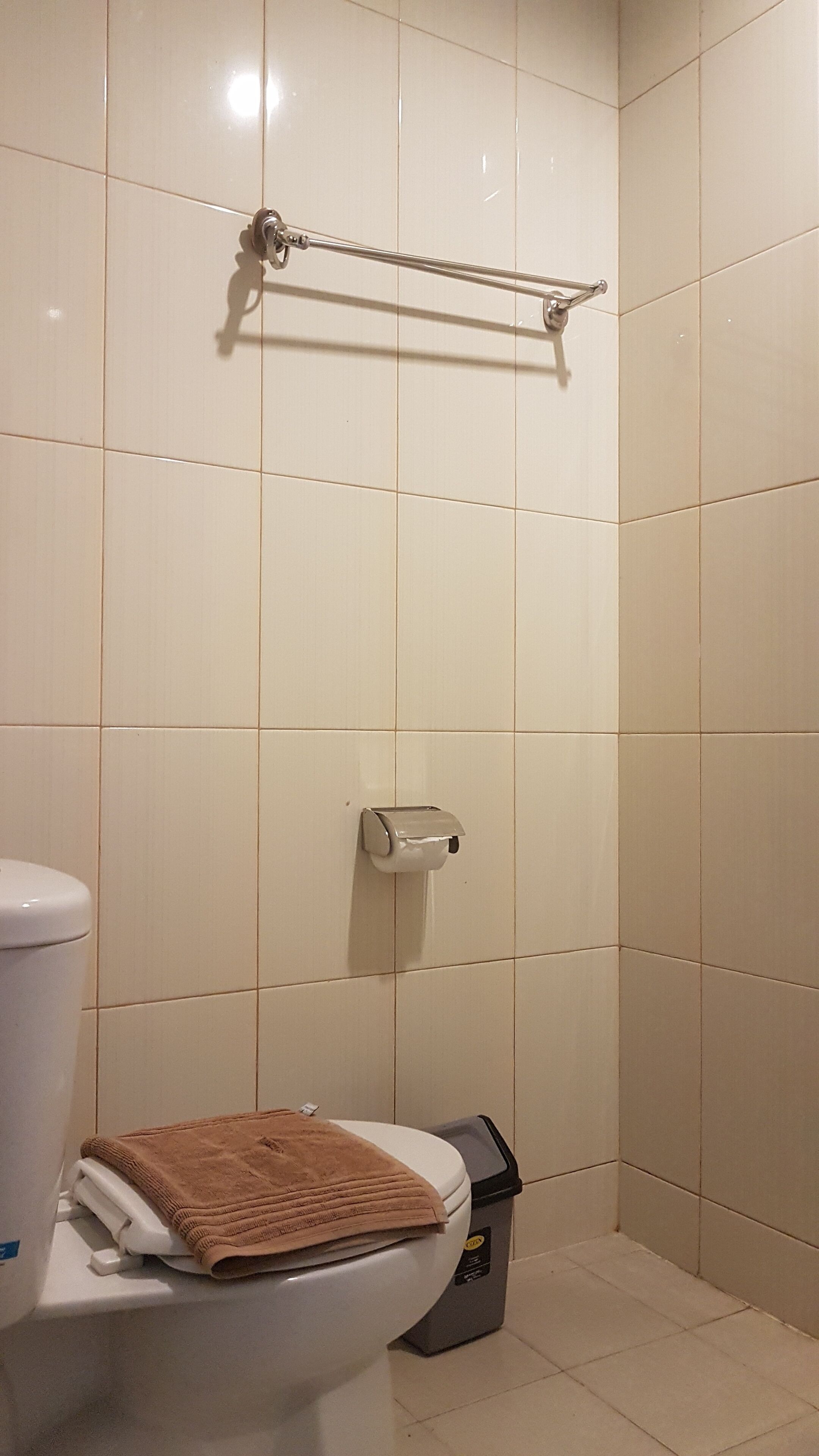 Une salle de bain équipée de toilettes, d’un porte-serviettes et d’une poubelle.