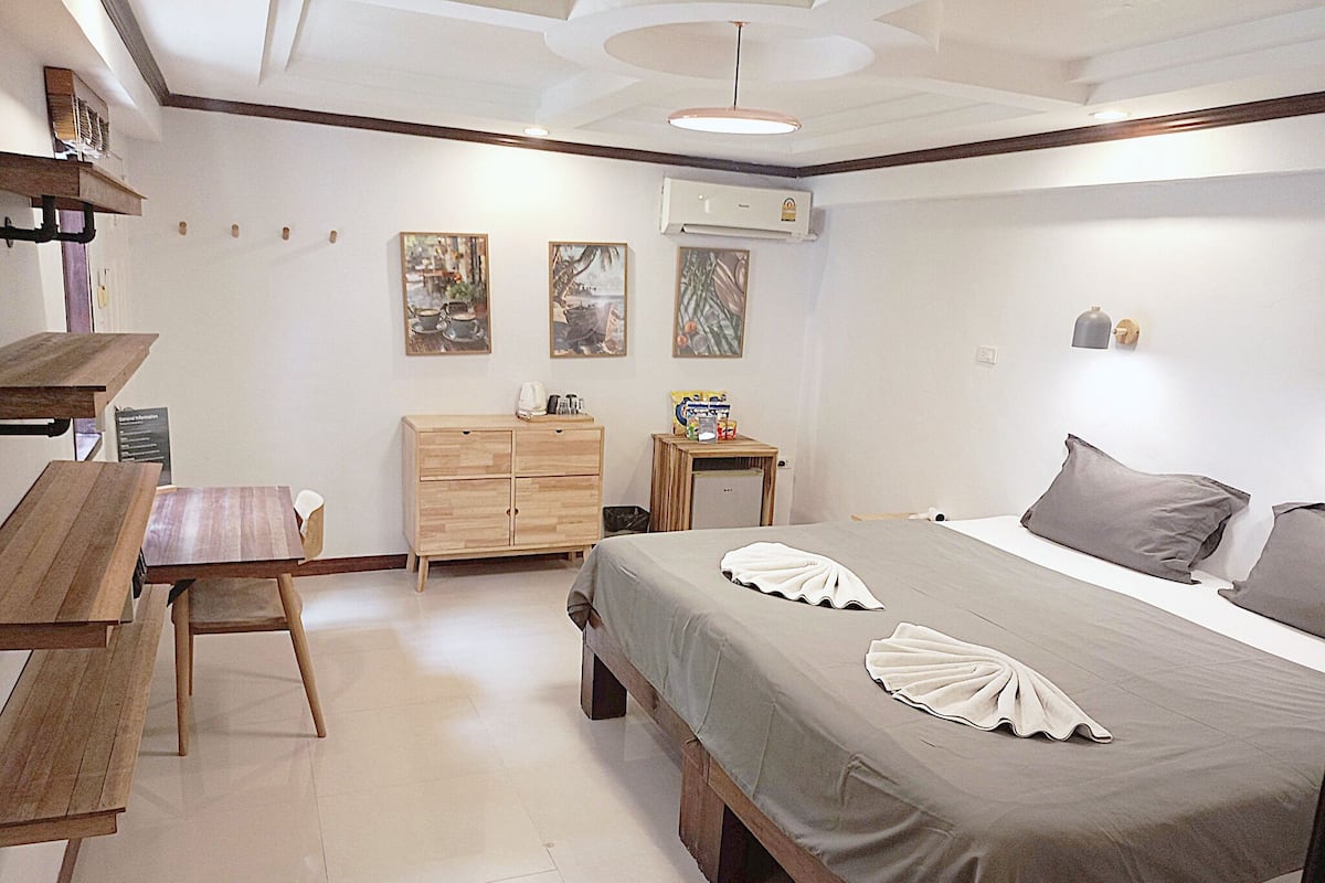 Une chambre à coucher comprenant un lit, un bureau en bois, une commode et deux climatiseurs fixés au mur.