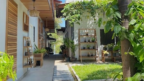 Un sendero estrecho bordeado por construcciones de madera, plantas en macetas y estantes.