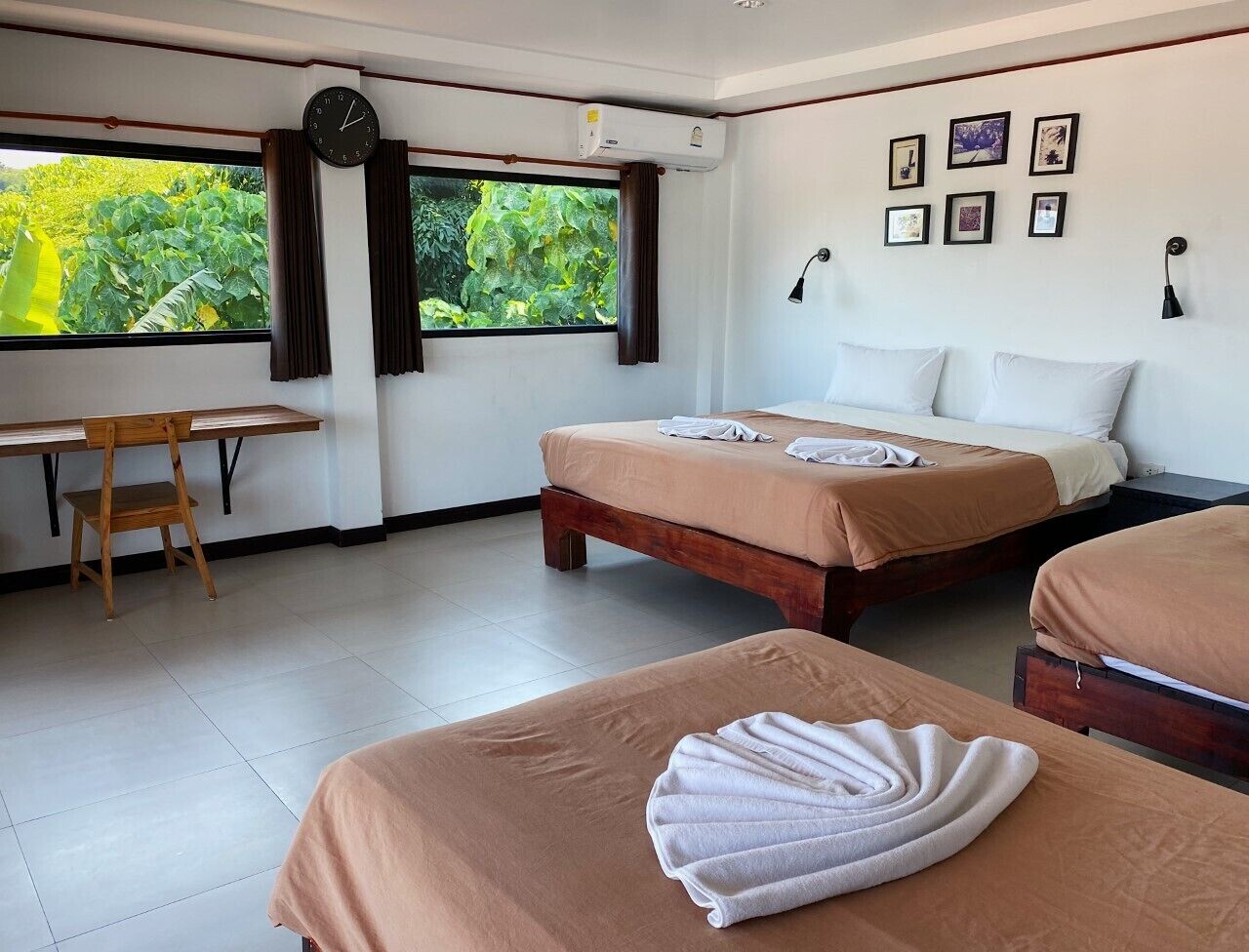 A hotel room with two beds, a desk, and a window with curtains.