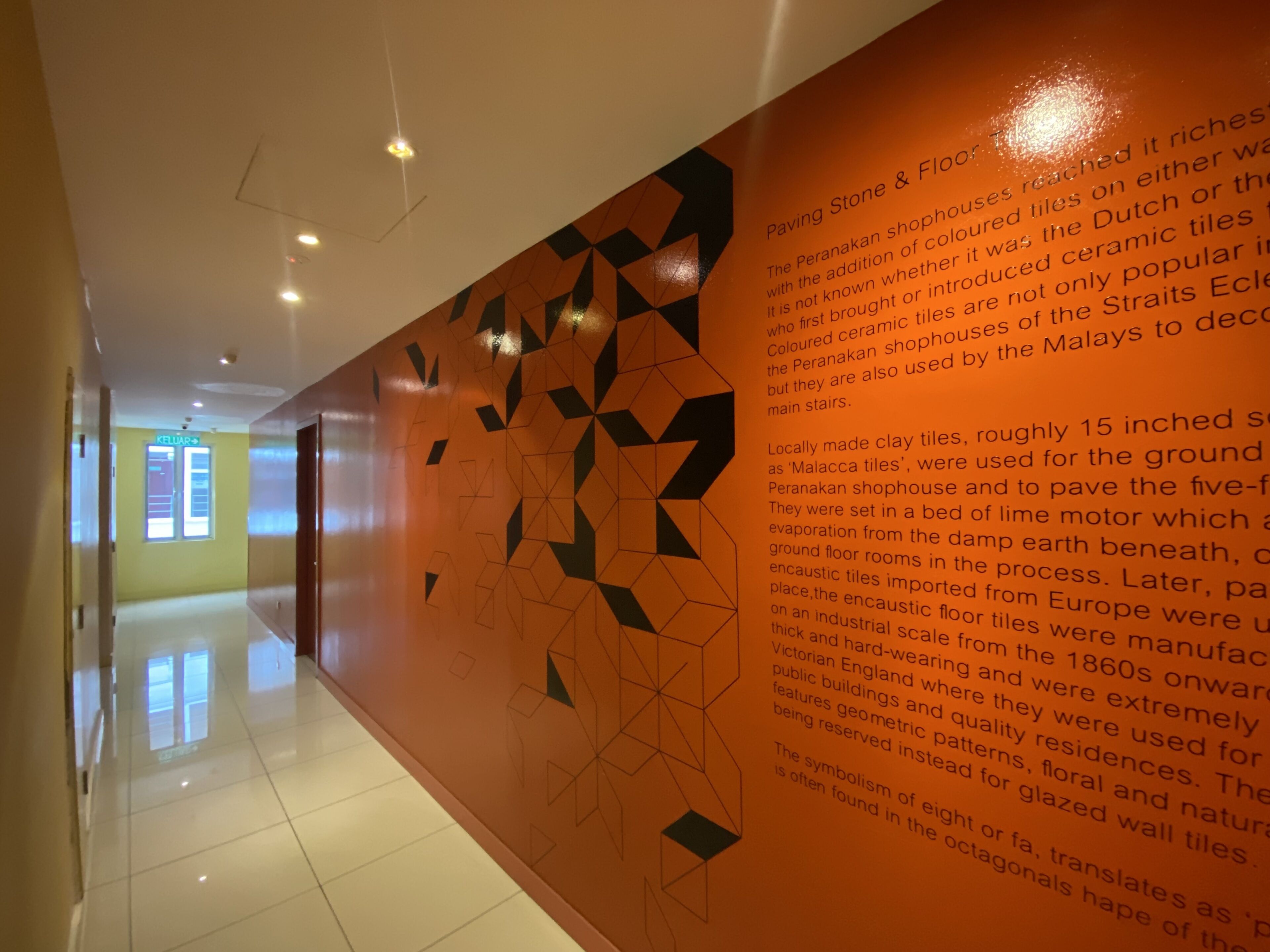 A hallway with a polished floor and a wall featuring geometric patterns and text about paving stone and floor tiles.