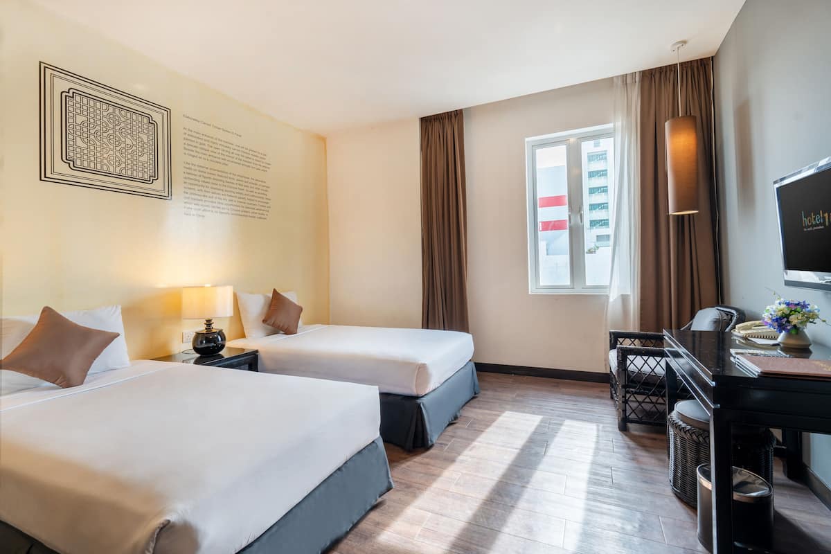 Habitación de hotel con dos camas, un escritorio, una silla, un televisor y una ventana con cortinas.