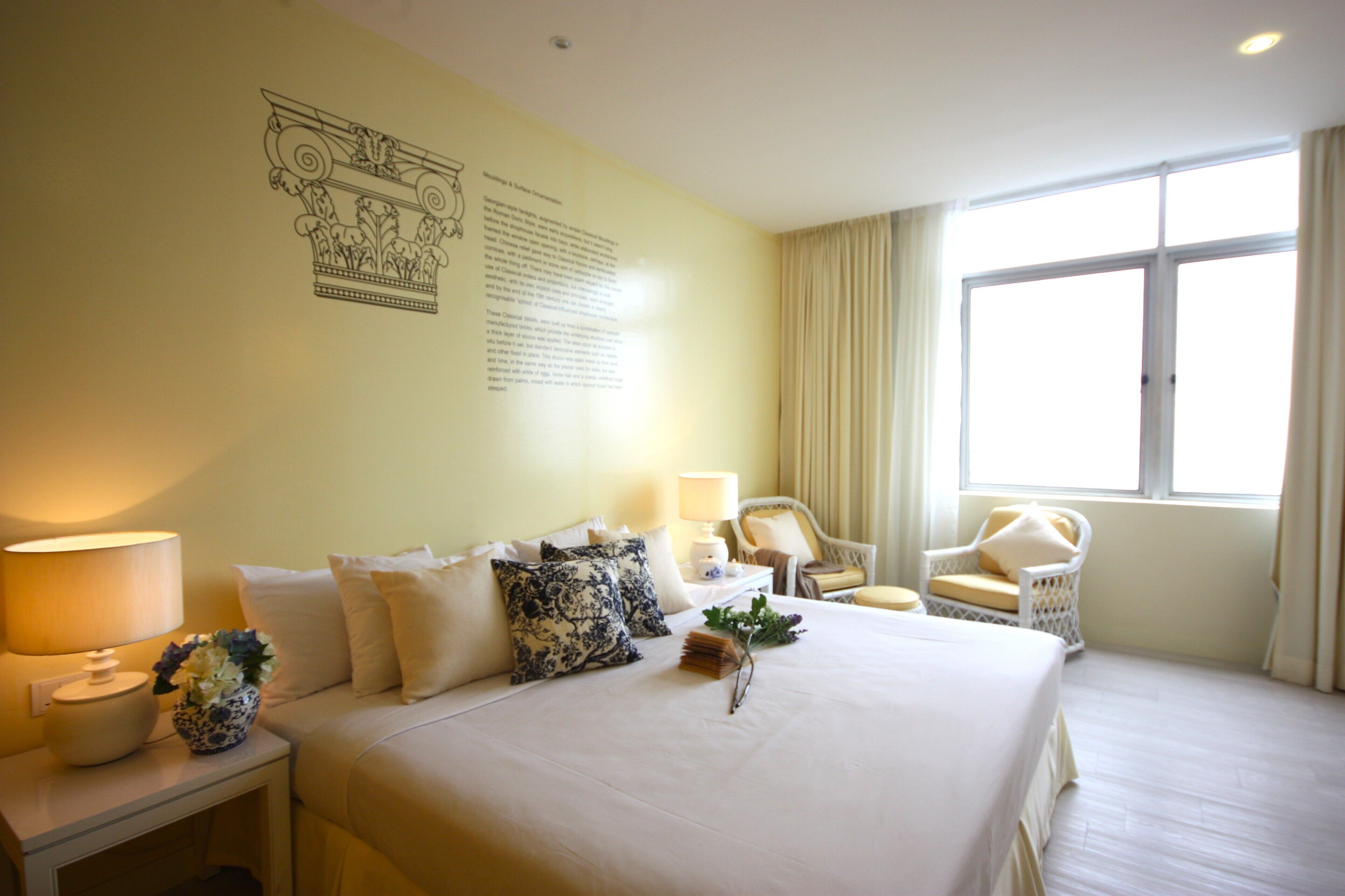 Une chambre d’hôtel avec un grand lit, deux tables de chevet, une chaise et une fenêtre avec des rideaux.