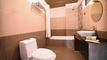 Un baño con inodoro, lavabo, ducha y un perchero para toallas.