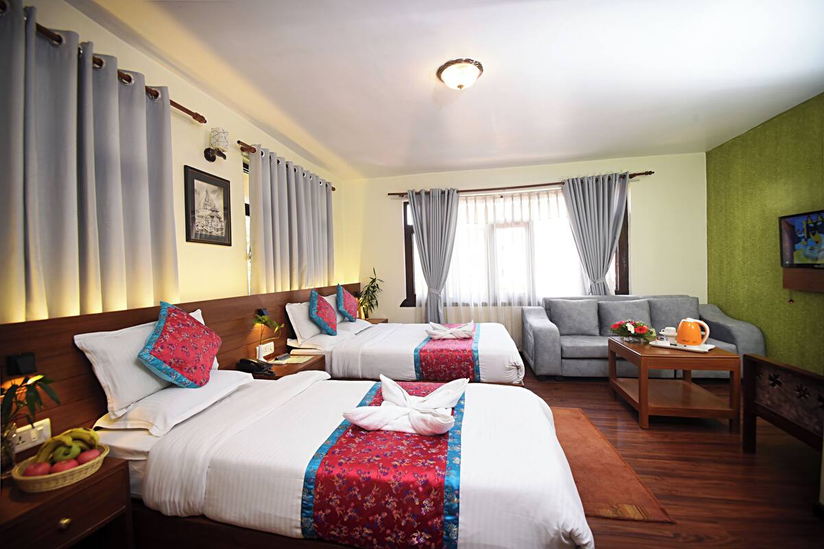 A hotel room with two beds, a sofa, a coffee table, and a dining table.