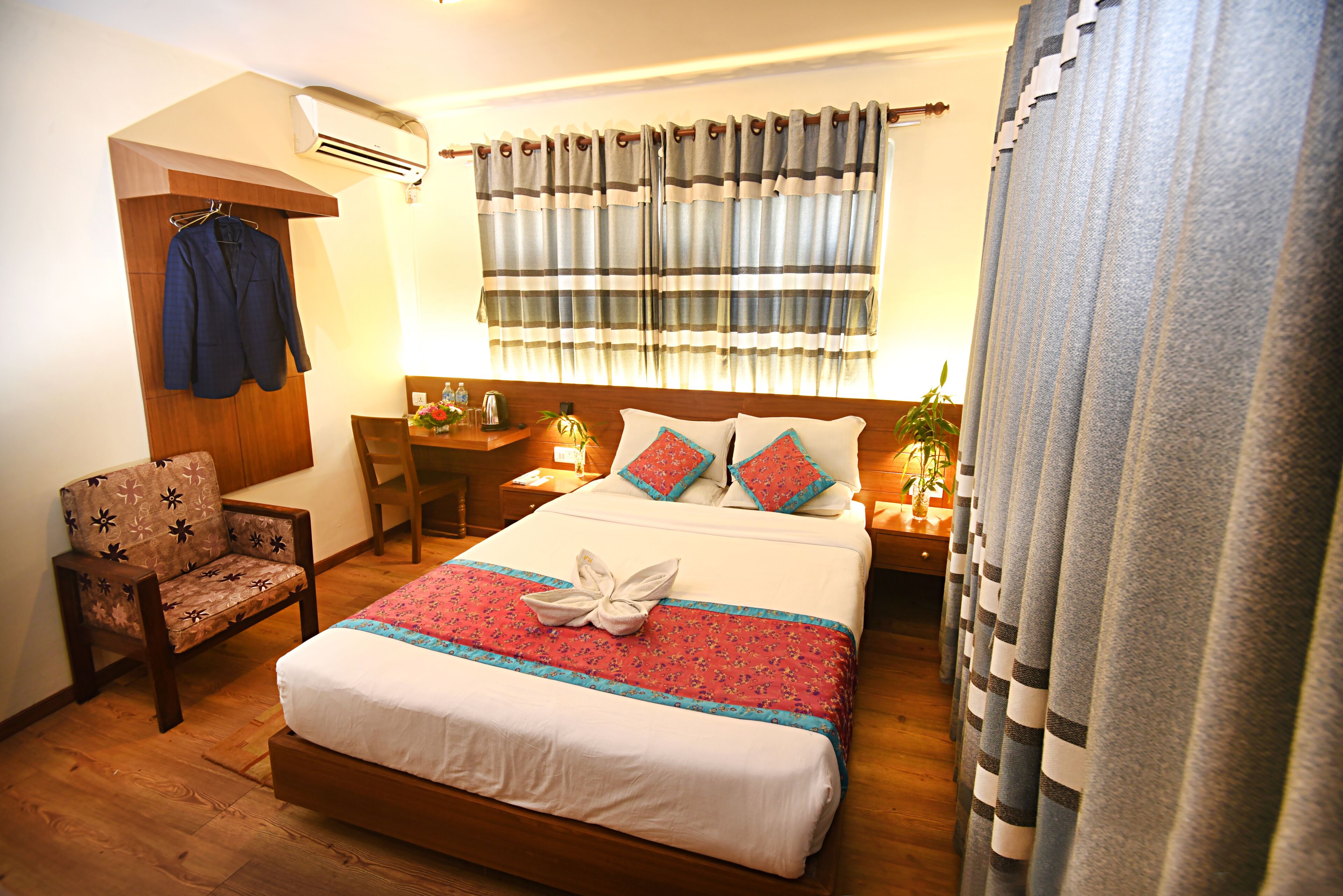 A neatly arranged hotel room with a bed, a chair, a desk, and a nightstand.