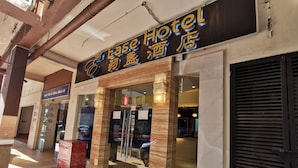 The exterior of the Ease Hotel with a sign in both English and another language, a glass entrance, and a closed shutter on the right. - Ease Hotel (Kota Kinabalu)