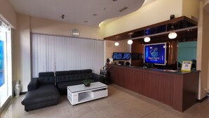 A modern hotel lobby with a reception desk, two televisions, a sofa, and a coffee table. - Ease Hotel (Kota Kinabalu)