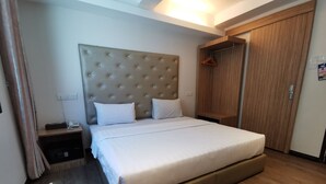 A hotel room with a large bed, a wooden wardrobe, a bedside table with a phone, and a nightstand. - Ease Hotel (Kota Kinabalu)