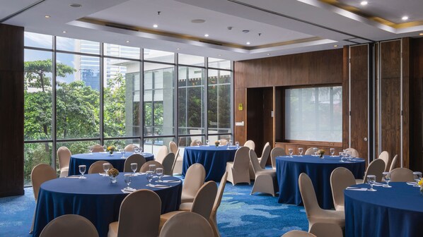A conference room with round tables, chairs, and a large screen.
