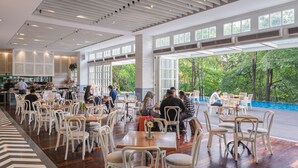 A spacious indoor dining area with natural light from large windows, white chairs, and a view of the outdoors. - Veranda Hotel Pakubuwono (Jakarta)