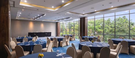 A conference room with round tables, chairs, and a stage.