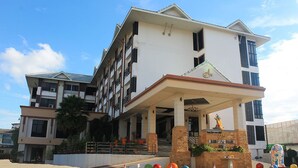Un hôtel à plusieurs étages, doté d’une entrée imposante, d’une statue et d’un espace paysager agrémenté de décorations sphériques aux couleurs vives.