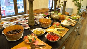 En buffet med forskellige retter og et stort vindue med udsigt til en bygning.