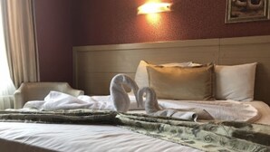 En pænt redt seng med gavl, vægmonteret lampe og et billede.