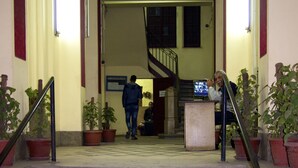Una escalera conduce a una zona de descanso con mostrador de recepción y plantas en macetas.