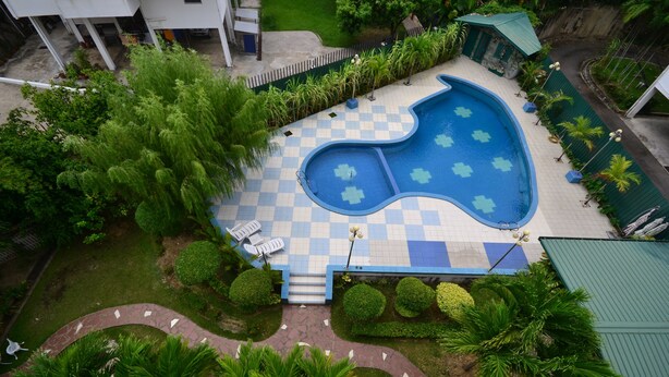 An aerial view of a swimming pool with a checkered pattern, surrounded by greenery and a small building with a green roof. - Lanvin Hotel (Kota Kinabalu)