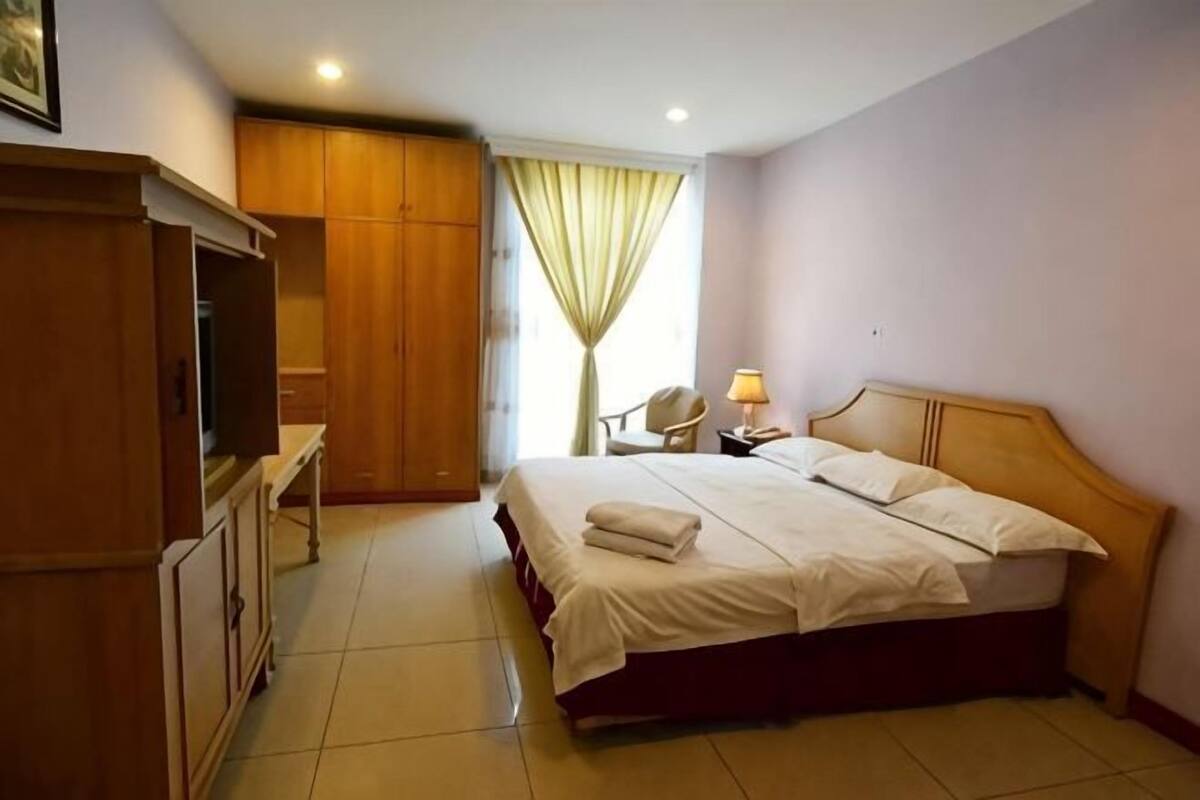 Une chambre d’hôtel avec un lit, un bureau, une armoire et une chaise.