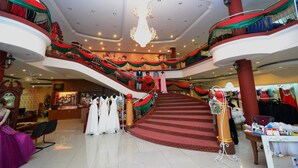 A multi-level shopping mall with a grand staircase, mannequins displaying dresses, and a chandelier. - Lanvin Hotel (Kota Kinabalu)