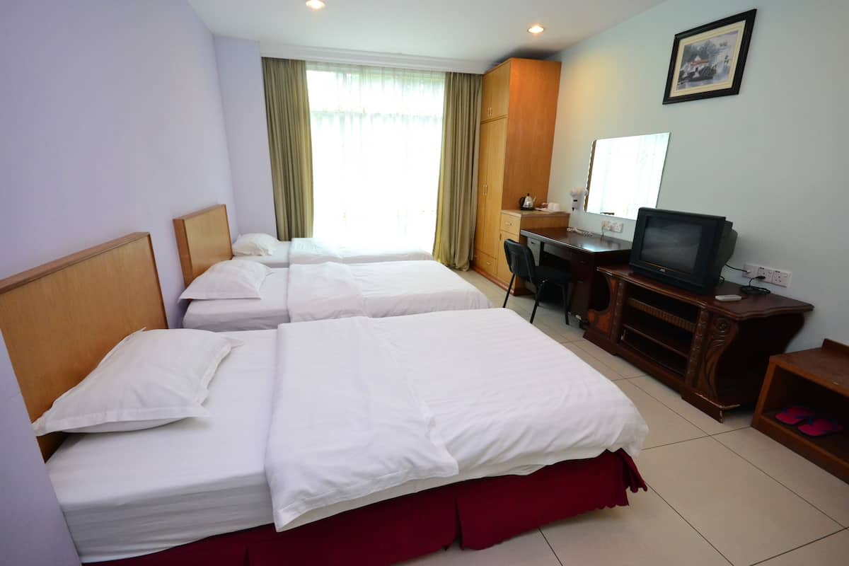 Une chambre d’hôtel avec deux lits, un bureau avec une télévision et une armoire.