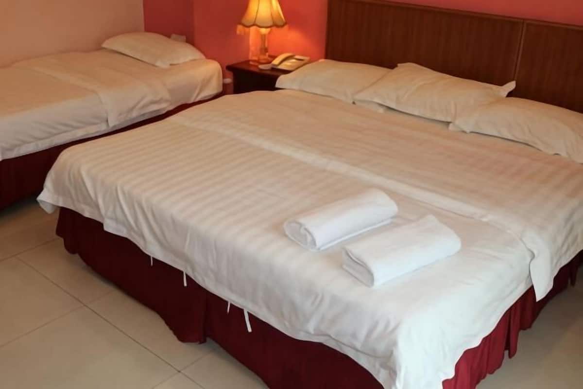 Une chambre d’hôtel avec deux lits, une table de chevet avec une lampe et un téléphone.