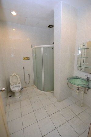 A bathroom with a toilet, a glass-enclosed shower, and a sink with a glass basin. - Lanvin Hotel (Kota Kinabalu)