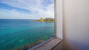 Vista desde una ventana sobre una zona costera con edificios a lo lejos.