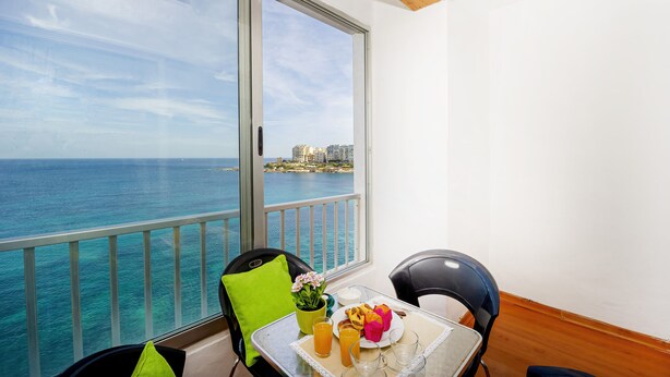 Un balcón con una mesa dispuesta para el desayuno, con vistas a la costa.