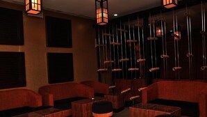 A dimly lit lounge area with red upholstered seating and wooden tables. - The Metropolitan Hotel Calabar (Calabar)