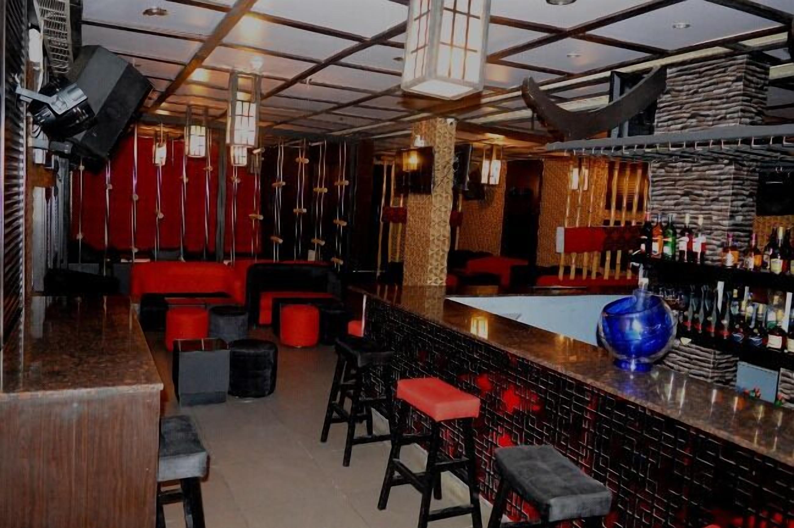 A bar area with red seating, a bar counter, and a blue decorative bowl.