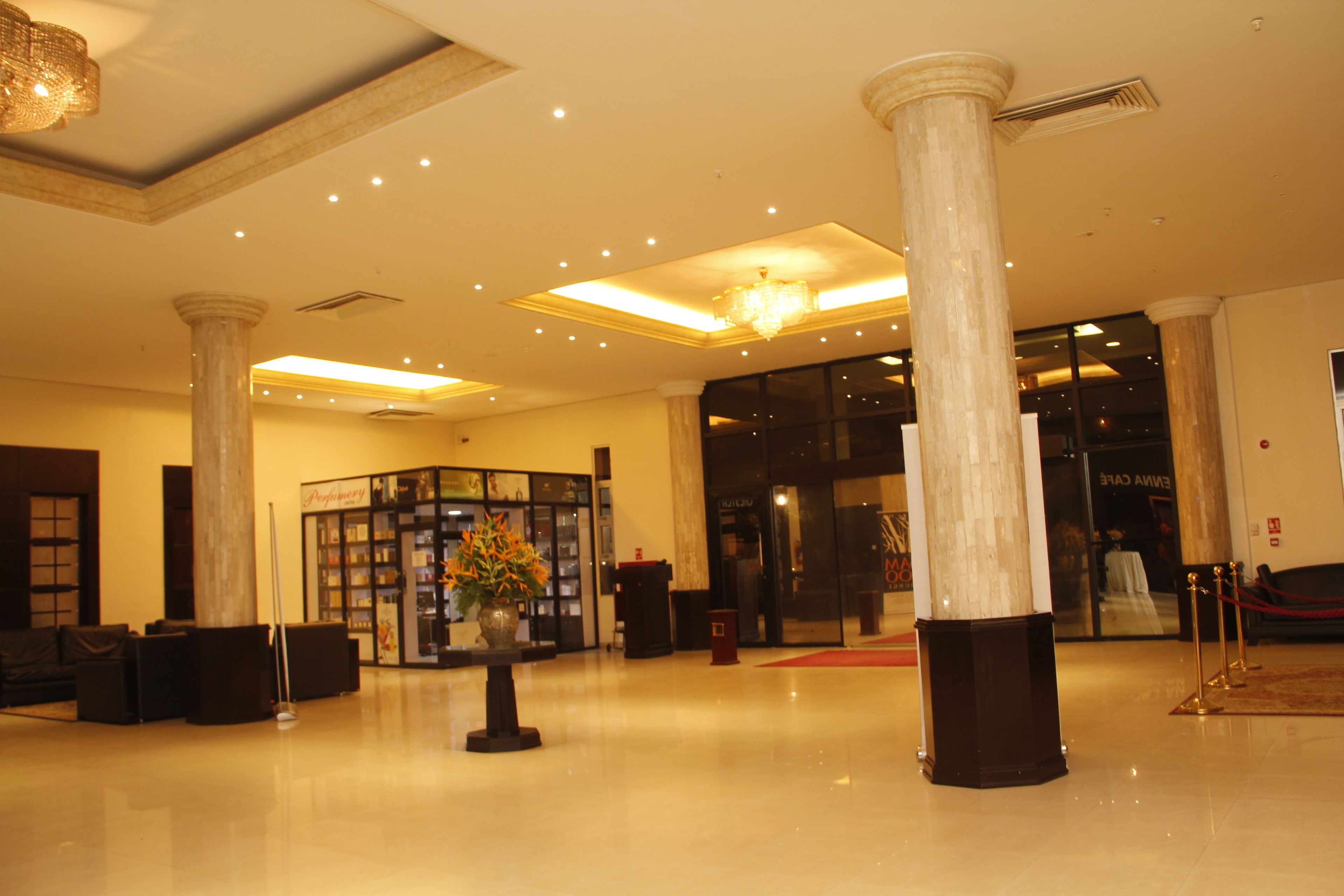 A spacious lobby with high ceilings, large columns, and a chandelier. There are seating areas and a reception desk.