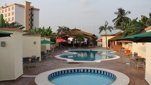 A pool area with multiple swimming pools, lounge chairs, and umbrellas. - The Metropolitan Hotel Calabar (Calabar)