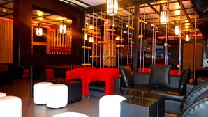 A modern lounge area with red and black seating, hanging lights, and a bar in the background. - The Metropolitan Hotel Calabar (Calabar)