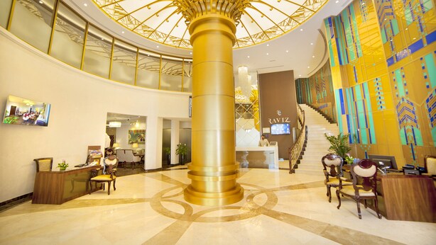 A lobby with a large golden column, a reception desk, and a staircase leading to upper floors. - Raviz Center Point Hotel (Dubai)