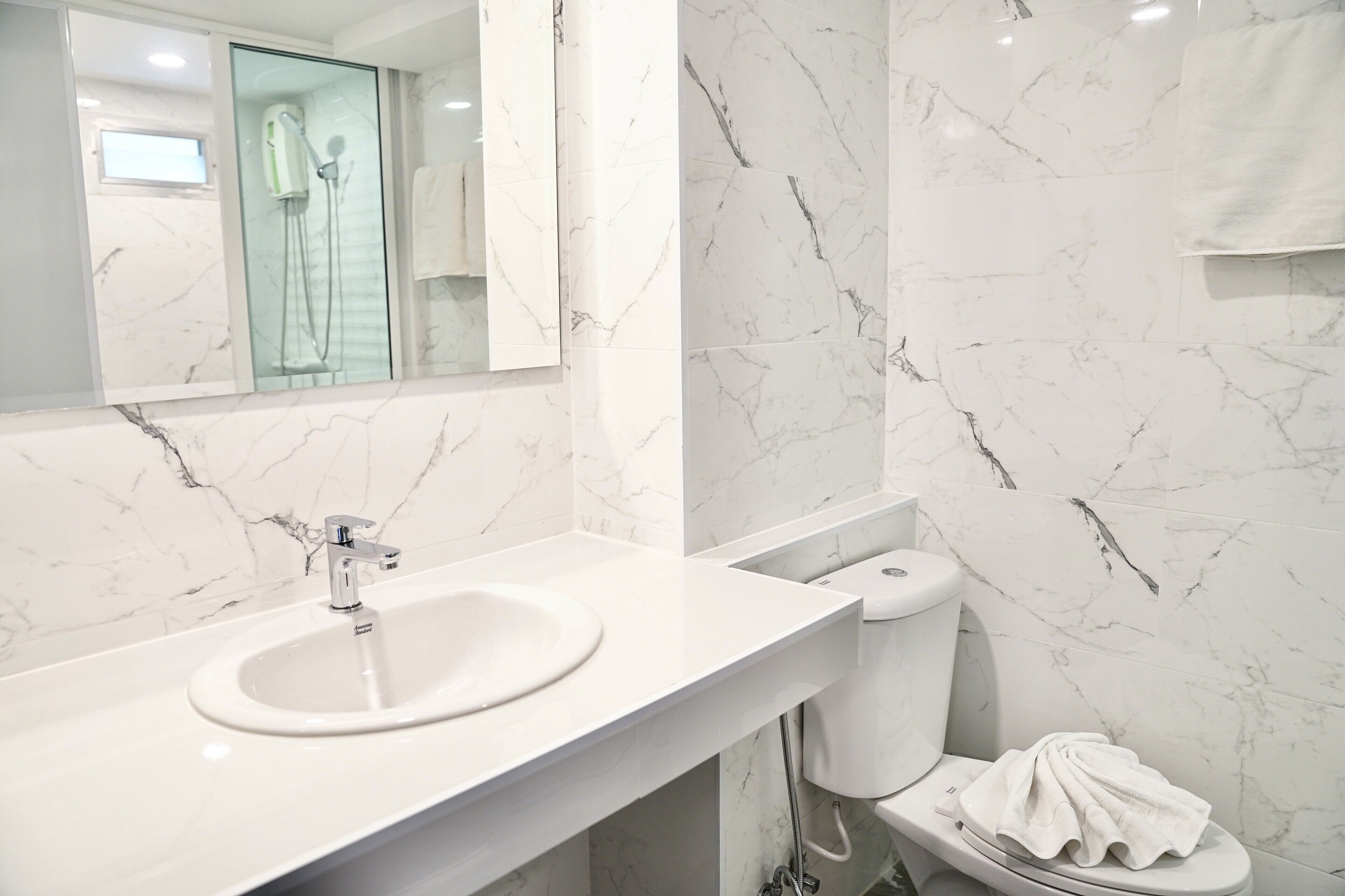 A modern bathroom with a white sink, a toilet, and a glass shower enclosure.