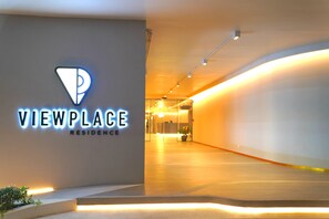 Une entrée moderne, avec un mur incurvé et une enseigne indiquant « VIEWPLACE RESIDENCE ».