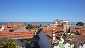 Un pueblo costero con edificios de tejados de terracota, un puerto deportivo y cielos azules despejados.