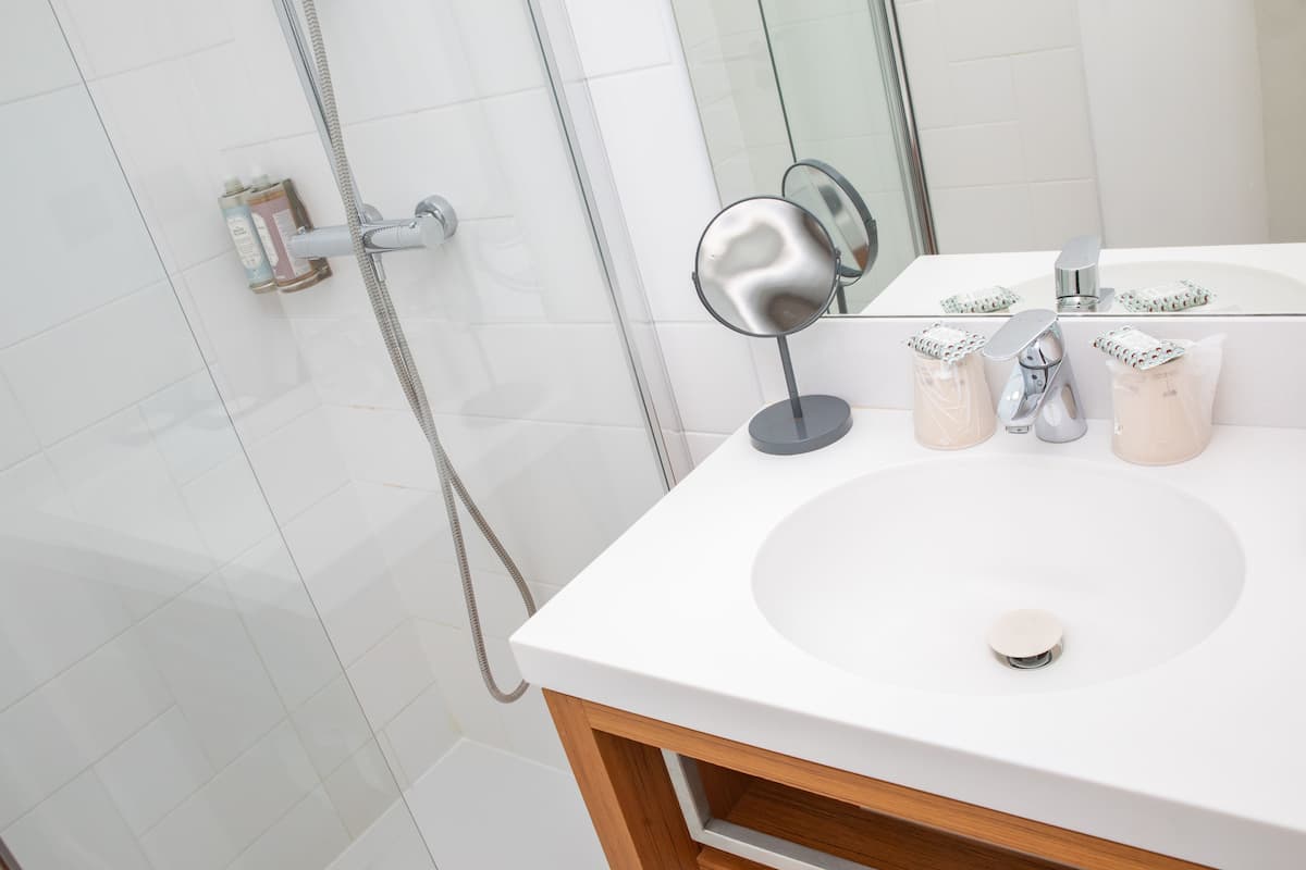 A bathroom with a white sink, a mirror, and toiletries on the counter.