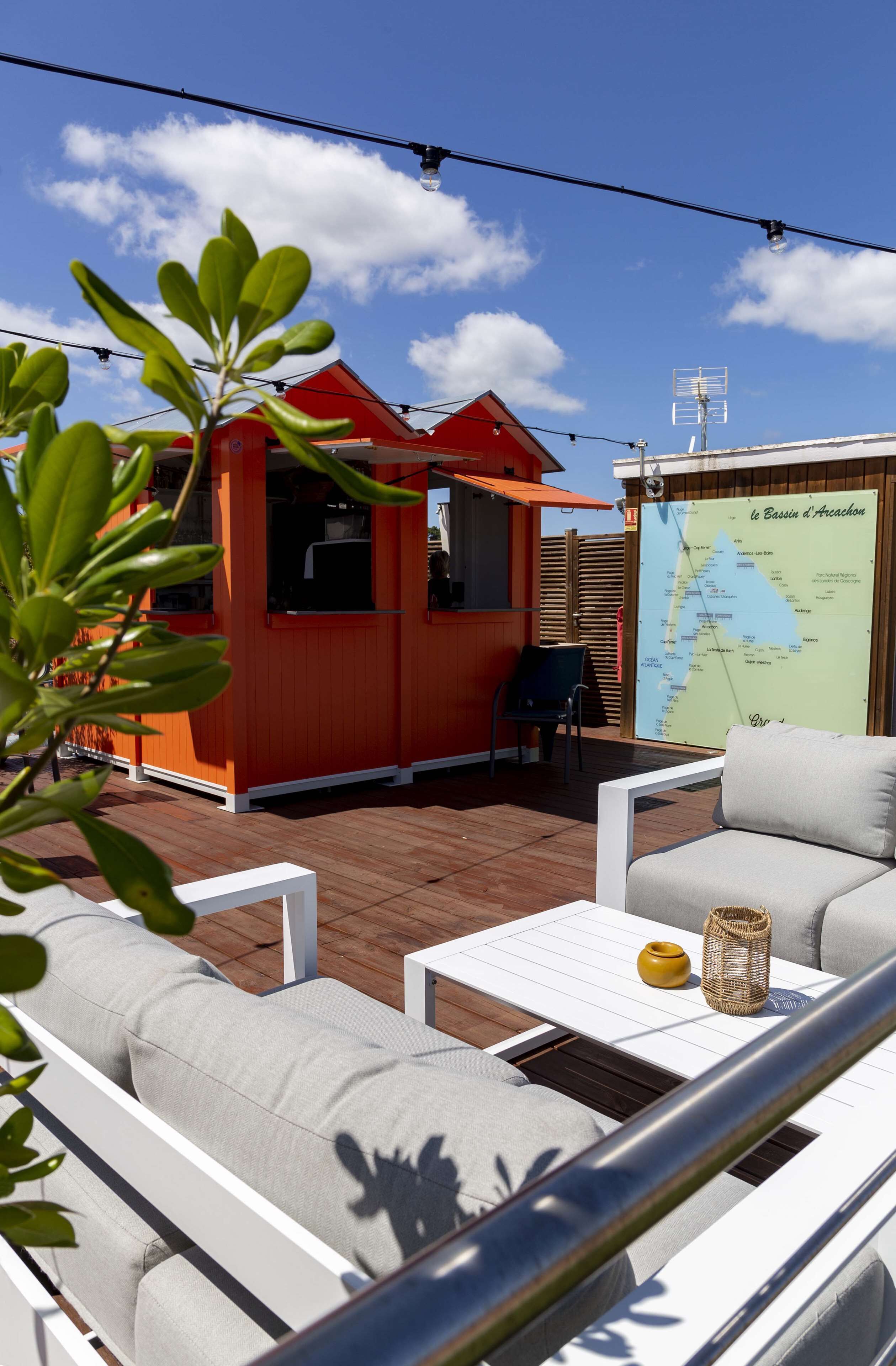 Une terrasse avec des sièges extérieurs, une carte et un bâtiment rouge.